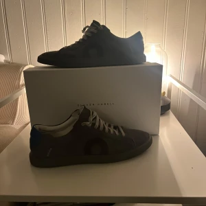 Grå sneakers från Oliver Cabell - Snygga grå sneakers från Oliver Cabell i modellen Low 1. Skorna har en stilren design med snörning och är tillverkade i mocka. Perfekta för en avslappnad stil. Skorna är använda endast 2 gånger och säljer de då de inte riktigt är min stil. Vid fler frågor tveka inte att höra av dig! 