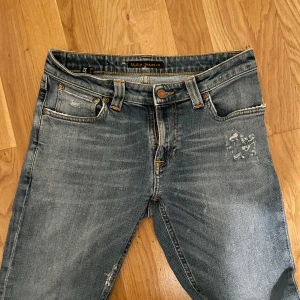 Nudie jeans - Säljer ett par Nudie Jeans i storlek 29/32. Modellen är slim fit, vilket ger en perfekt passform utan att vara för tighta. Jeansen är ljusblå med snygga slitningar. Skick 8,5/10.
