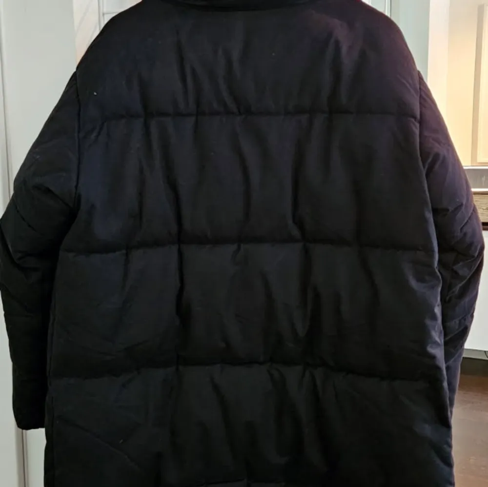 Säljer en svart dunjacka från Monki i storlek XS. Jackan har en hög krage och knäppning framtill. Perfekt för kalla dagar med sin långa passform och vadderade design. En stilren och praktisk jacka för vintern. . Takit.