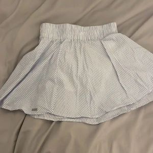 Randig kjol från Aimn - Säljer en söt blå- och vitrandig kjol från Aimn i storlek XS. Kjolen har en elastisk midja och har inbyggda shorts under! 