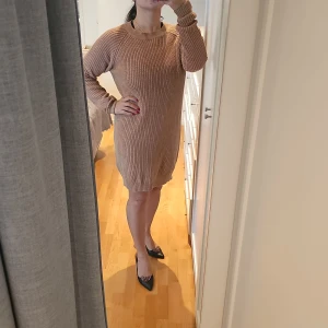 Beige stickad klänning från Noisy May - Mysig beige/brun stickad klänning från Noisy May. Perfekt för kyligare dagar med sin långa ärm och bekväma passform. Klänningen har en enkel design som gör den lätt att matcha med olika accessoarer. Ett måste i garderoben för en stilren look!