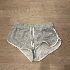 Grå shorts med vit kant - Säljer ett par grå shorts med vit kant och snörning i midjan. .Ska flytta snart så vill gärna bli av med allt så fort som möjligt (pris kan diskuteras)💕