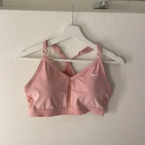 Rosa sporttopp från Nike - Säljer en rosa sporttopp från Nike med justerbara axelband och en liten vit logga på framsidan. Perfekt för träning och ger bra stöd. Ska flytta snart så vill gärna bli av med allt så fort som möjligt (pris kan diskuteras)💕