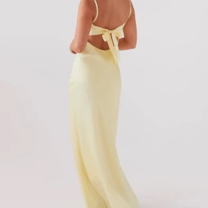 Vacker Gul långklänning med knyt vid ryggen  - Säljer en elegant gul långklänning med smala axelband och knytning i ryggen. Klänningen har en v-ringad design och är perfekt för sommarens festligheter eller en studentbal. Materialet är satin, klänningen har aldrig använts:) 