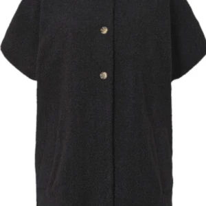 Svart teddyjacka från Hope - Säljer en svart teddyjacka från SAND med kortärmad design och knappar framtill. Perfekt för en stilren look med en mysig känsla. Jackan har en enkel och elegant stil som passar till många tillfällen.