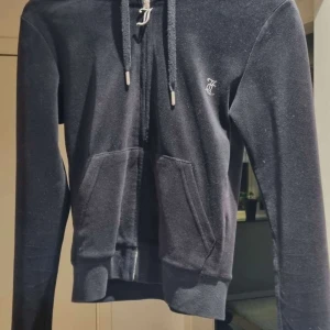 Juicy Tröja  - Säljer en äkta Juicy Couture hoodie i storlek XS. Den är svart och har "Juicy" i strass på ryggen, en riktigt klassisk och tidlös design! Hoodien är använd men i mycket gott skickt. Inga fläckar eller hål. 
