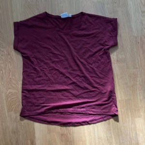 Vinröd top från VILA - Säljer en vinröd topp från VILA i storlek S. Toppen har en enkel design med korta ärmar och rund hals. Perfekt för en avslappnad stil.