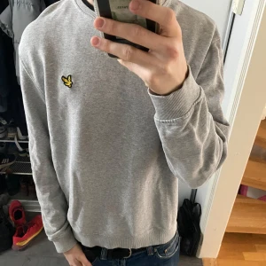 Grå sweatshirt från Lyle & Scott - Säljer en stilren grå sweatshirt från Lyle & Scott med deras ikoniska logga på bröstet. Tröjan har långa ärmar och ribbade muddar vid ärmslut och nederkant. Perfekt för en avslappnad look. Tröja är i mycket bra skick utan defekter. Storleken är L men sitter mer som en M. Nytt pris: 849kr mitt pris: 300 kr. Tveka inte på att höra av dig om du är intresserad!
