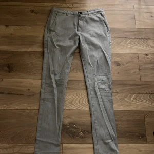 Beige kostymbyxor - Snygga beige kostymbyxor med en klassisk design. De har en knapp och dragkedja framtill samt fickor både fram och bak. Perfekta för en stilren look.