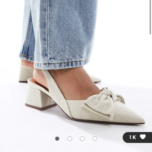 Söker!!! - Snygga beige klackskor med en elegant rosett på framsidan. Skorna har en spetsig tå och en bekväm blockklack, perfekt för att ge en stilren look. Passar utmärkt till både jeans och klänning.