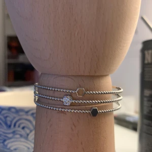 Silverfärgade armband med hexagon och hjärta - Snygga silverfärgade armband med minimalistisk design. Ett armband har en hexagonformad detalj och ett annat har ett hjärta. Perfekta för att bära flera tillsammans för en stilren look.