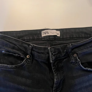 Svarta jeans från Zara - Snygga svarta lågmidjade jeans från Zara med en klassisk design. De har en dragkedja och knapp framtill samt fem fickor. Perfekta för en stilren look.