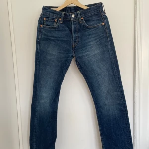Levis 501 jeans - Klassiska Levis 501 jeans i en snygg blå tvätt. De har en rak passform och är tillverkade i slitstarkt denim. Perfekta för en avslappnad stil med fem fickor och knappgylf.