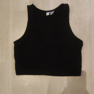 Svart ärmlös linnetopp  - Säljer en stilren svart ärmlös linnetopp från Divided. Perfekt för varma dagar eller som ett lager under en jacka. Toppen har en enkel och klassisk design som passar till det mesta. Hör av dig vid intresse!