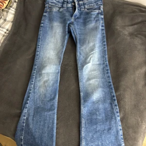 Blå bootcut jeans från H&M - Snygga blå low waist bootcut jeans från H&M med justerbar midja. 