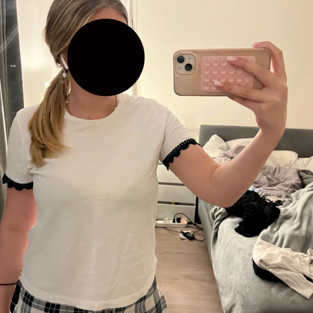 Säljer en vit t-shirt med svarta spetsdetaljer vid ärmsluten. Perfekt för en stilren och enkel look. Passar bra till både jeans och kjol.. Yläosat.