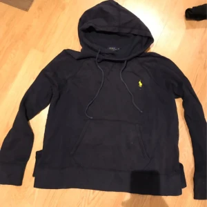 Hoodie Ralph Lauren - Säljer en snygg hoodie från Ralph Lauren med det klassiska logotypbroderiet på bröstet. Tröjan har en stor ficka framtill och justerbar huva med dragsnören. Perfekt för en avslappnad stil.