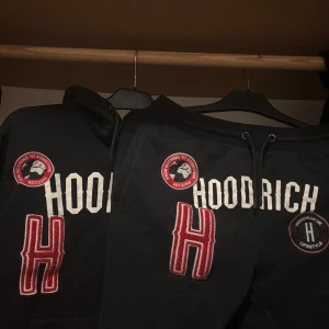 Svart set från hoodrich - Säljer ett svart sett från Hoodrich med stora vita bokstäver och röda detaljer. Hoodien har en stor ficka framtill och en justerbar huva. Perfekt för en avslappnad stil.