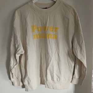 Beige sweatshirt med texten 'Power mama' - Säljer en beige sweatshirt med texten 'Power mama' i gult på framsidan. Tröjan har långa ärmar och en rund halsringning med ribbade muddar vid ärmslut och nederkant. Perfekt för en avslappnad stil.