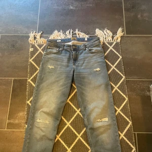 Blå jeans från Jack & Jones - Säljer jeans från Jack & Jones snygga slitningar. Inga defekter och jeansen är i storlek 176/16 years old. Men passar yngre