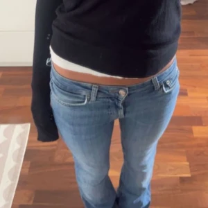 Blå jeansbyxor - Snygga blå jeans med låg midja och bootcut-stil. Perfekta för en avslappnad look. Klassisk femficksdesign med knapp och dragkedja framtill.