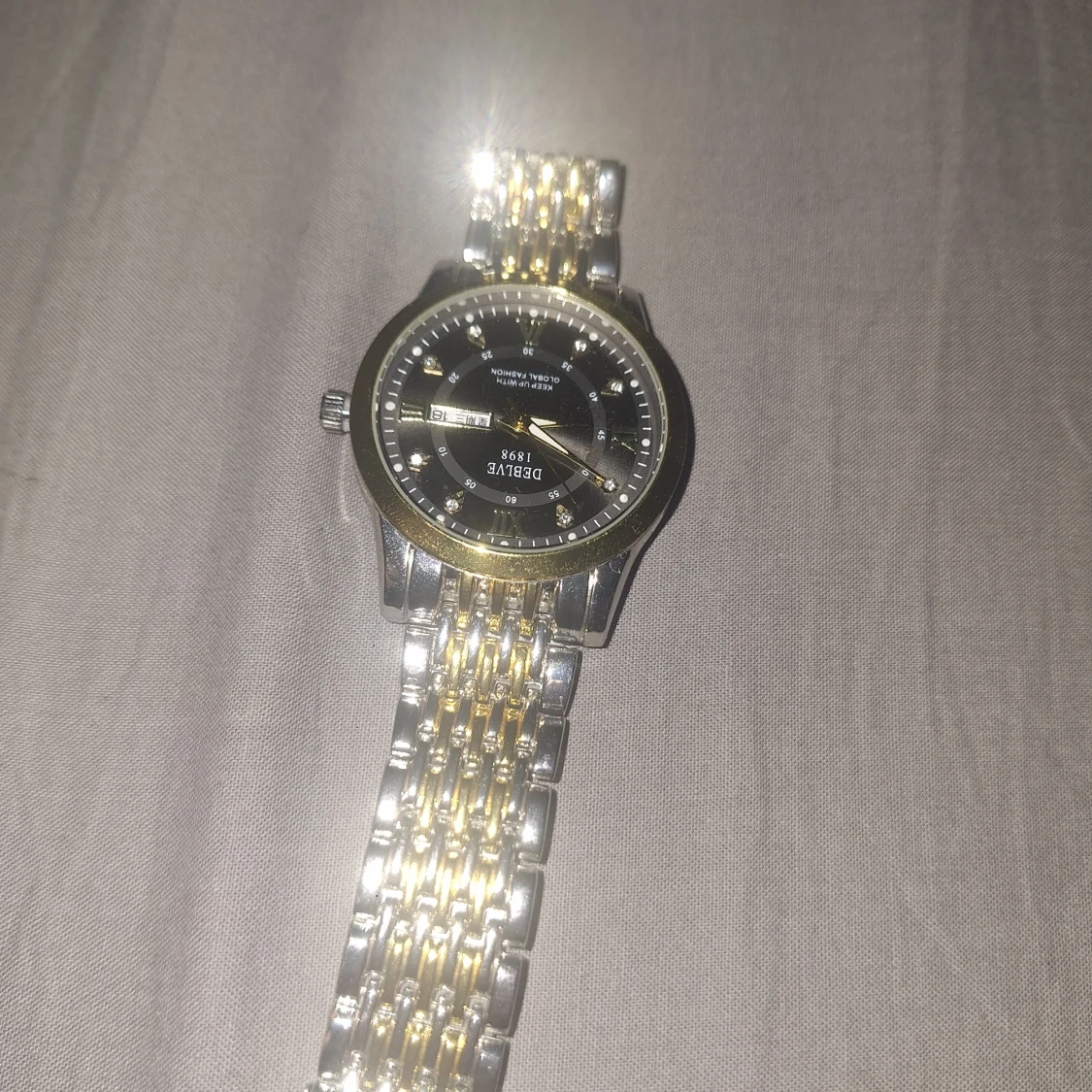 Guld och silver klocka med svart urtavla