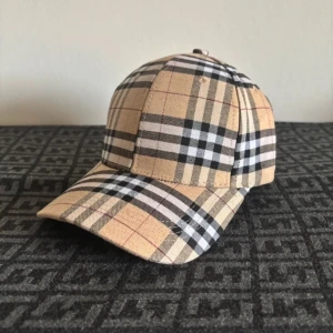 Helt ny keps - Snygg keps med klassiskt rutigt mönster i beige, svart och vit. Kepsen har en justerbar rem baktill med metallspänne för perfekt passform. Perfekt accessoar för en stilren look. Även Perfekt för sommaren. Priset är ej hugget och kan gå ner vid snabb affär.