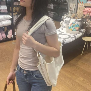 Beige shoppingväska i bomull - Säljer en praktisk beige shoppingväska i bomull. Väskan har flera fack och långa handtag för enkel bärning. Perfekt för att bära med sig allt man behöver under dagen. Enkel och stilren design som passar till det mesta.