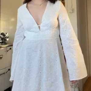 Studentklänning,Vit klänning med öppen rygg - Säljer en söt vit klänning med v-ringning och öppen rygg. Klänningen har långa ärmar och ett fint broderat mönster. Perfekt för sommarens alla tillfällen eller till studenten! Sälje den pga felköp o finns i 36 & 38, endast testad 