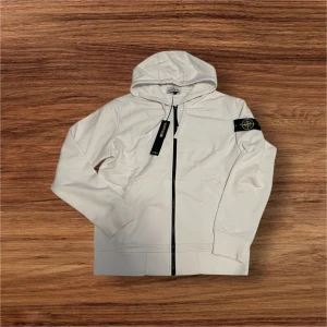 Vit Stone Island Kofta - Storlek Large - Ny Med Taggar  - Säljer en helt ny, vit Stone Island kofta i storlek Large. Koftan är i toppskick och har taggarna kvar. Perfekt för dig som vill ha en stilren och kvalitativ tröja från ett av de mest ikoniska märkena.