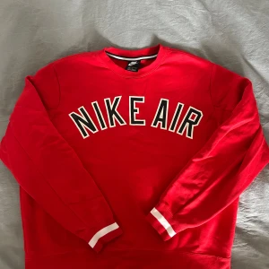 Röd Nike Air sweatshirt - Säljer en snygg röd Nike Air sweatshirt med stort tryck på framsidan. Tröjan har långa ärmar och en klassisk rund halsringning. Perfekt för en sportig look eller avslappnad stil. 🏀