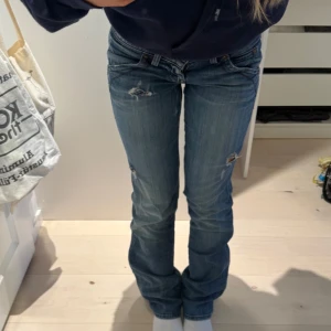 Snygga lågmidjade jeans från Guess - Snygga blå jeans från Guess med slitningar. De har en låg midja och är bootcut/straight. Midjemått tvärsöver: 37cm (passar mig som har 33 i midjemått) - Innerbenslängd 83cm 💗/ Pris går att diskuteras!