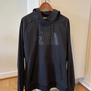 Svart vår/höst jacka från The North Face - Säljer en stilren svart vår/höst jacka från The North Face. Den har en klassisk design med en stor logga på framsidan och en praktisk känguruficka. Perfekt för kyliga dagar med sin bekväma passform och justerbara huva. Passar både till vardags och utomhusaktiviteter. Något större i storleken, den är en S men passar mig. Jag är 180cm lång