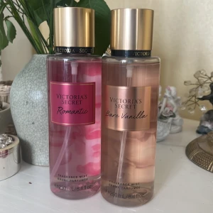Victoria's Secret Fragrance Mist - Två doftsprayer från Victoria's Secret: 'Romantic' med noter av rosa blomblad och mysk, och 'Bare Vanilla' med vispad vanilj och mjuk kashmir. Båda flaskorna är 250 ml och har en elegant design med guldlock.