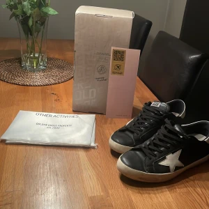 Svarta sneakers från Golden Goose - Snygga svarta sneakers från Golden Goose med vit stjärndetalj på sidan. Skorna har en klassisk snörning och vit sula. Perfekta för en stilren look. Inga defekter förutom det cresset ni ser på bilden!, pris kan diskuteras!