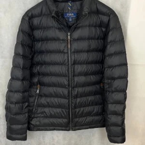 Svart jacka från Polo Ralph Lauren - Snygg svart jacka från Ralph Lauren. Originellt storlek L men sitter bra storlek M också. Väldigt bra skick förutom en liten defekt på insidan av jackan (se sista bild). Priset kan diskuteras