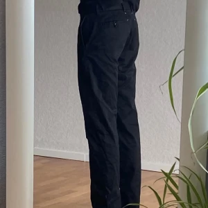 Svarta byxor från Maison Margiela - Snygga svarta byxor från Maison Margiela. Kroken i byxmynningen är omsydd hos skräddare då den normalt sitter löst. Vill inte riskera att den åker av. Size 48.