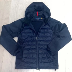 Mörkblå jacka med huva från Polo - Snygg mörkblå jacka från Polo med huva och dragkedja. Jackan är knappt använd och är vind och regntålig. Funkar bra för både vår och höst.       Pris kan diskuteras