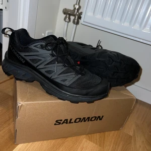 Salomon XT-6 EXPANSE - Säljer ett par svarta Salomon XT-6 Expanse sneakers. De är unisex och något små i storleken, inte fel att ta dessa om du vanligtvis har 41 i herrskor. Jag brukar ha 42 och kan ha dessa, men de är lite tajta. Skicket är mycket bra, inget slitage då de knappt har använts. Nypris är i skrivande stund 1990kr.