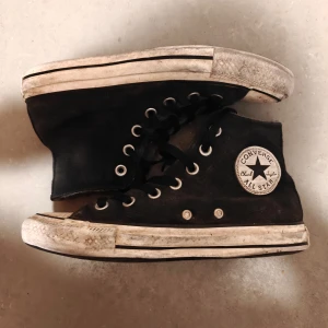 Svarta Converse All Star sneakers - Säljer ett par klassiska svarta Converse All Star sneakers med vit sula och snörning. Skorna har en hög modell och är fodrade för extra värme. Perfekta för en avslappnad stil.