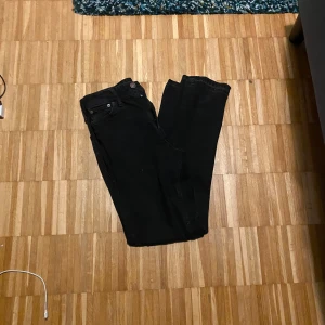 Svarta jeansbyxor från Jack And Jones  - Snygga svarta jeansbyxor med loose fit. De har en klassisk design med knappar och dragkedja framtill. Perfekta för en avslappnad stil. Modell Loose Chris, passar 30,32