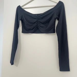 Offshoulder topp  - Snygg svart ribbad offshoulder topp från NLY One. Toppen är croppad med långa ärmar.
