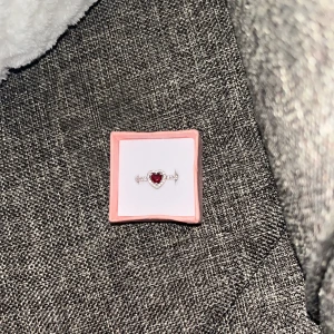 Pandora ring - Elegant Pandora silverring med en röd hjärtformad sten i mitten, omgiven av små glittrande stenar. Perfekt för att ge en romantisk touch till din stil. Ringen kommer i en söt rosa ask. Den är i storlek 16,5 mm