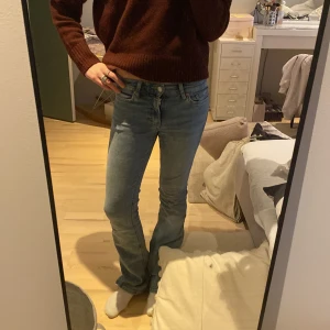 Blå bootcut jeans - Säljer ett par klassiska blå bootcut jeans. De har en hög midja och en snygg passform som sitter tight upptill och blir vidare nedtill. Perfekta för en avslappnad stil med en touch av retro.