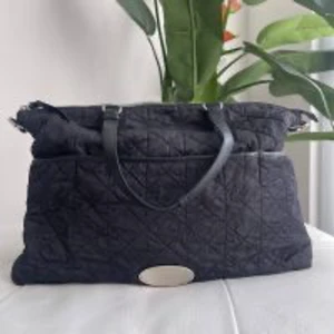 Mulberry Black Nylon “Rosie” baby changing bag - Mulberry Rosie Black babyskötväska med silverdetaljer Mycket bra skick, ren och lätt använd En vacker designerväska för bebisar Inkluderar justerbar canvasrem Denna fantastiska väska är quiltad i robust svart nylon och kantad med läder, med silverdetaljer. Den har en innerficka med dragkedja och två innerfickor. Att nämna – • Hårlinjer på detaljerna • Små, knappt synliga drag i nylonet 