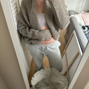 Beige stickad kofta från Redsoul - Mysig beige stickad kofta från Redsoul. Perfekt för kyliga dagar med sin avslappnade passform och långa ärmar. Koftan har en grovstickad struktur som ger en trendig look. Ett måste för garderoben!