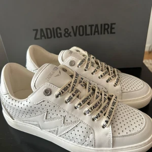 Vita sneakers från Zadig & Voltaire - Snygga vita sneakers från Zadig & Voltaire LA Flash med originalsnören och originalkartong. Skorna är använda ett fåtal gånger så de är i mycket bra skick. Nypris 3900.