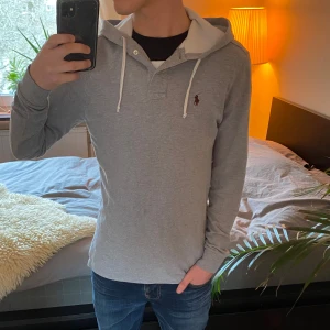Ralph Lauren Hoodie - Säljer denna sjukt snygga och unika hoodie från Polo Ralph Lauren med en liten broderad logga på bröstet. Tröjan har en sjukt unik design med en huva med snören samt knappar som liknar en krage på en polo tröja. Hoodien är lite tunnare i materialet men passar perfekt under majoriteten av året och är riktigt snygg att layera med. Tröjan har inga tecken på slitage utöver att den är använd såklart och befinner sig därav i skicket 8.5/10. Tveka inte på att höra av dig vid frågor eller funderingar! ⭐️