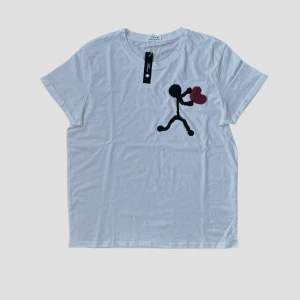 Heartgiver T-Shirt - Snygg vit t-shirt med ett coolt tryck av en stickman som håller ett rött hjärta. Perfekt för en avslappnad stil och sommarn. T-shirten har en normal passform och korta ärmar.