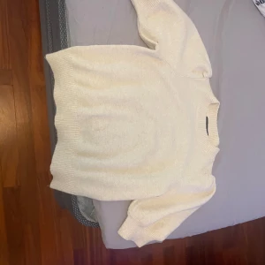 Vit stickad tröja från Vero Moda - Säljer en söt vit stickad tröja från Vero Moda i storlek XS. Tröjan har korta ärmar och ribbade kanter vid ärmslut, halsringning och nederkant. 